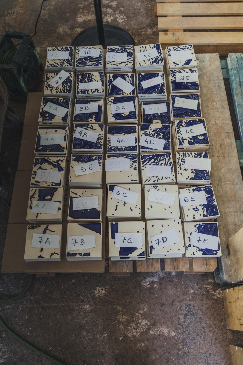 Vhils × Clay Rasura tile edition laid out at the factory — cobalt carved tiles