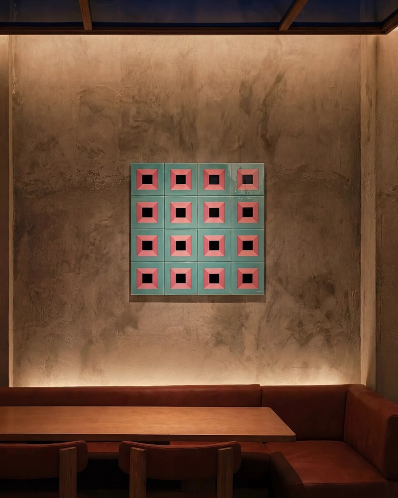 Catalogue render — a sixteen-tile BLACKDOORS panel on a plaster wall in a restaurant interior