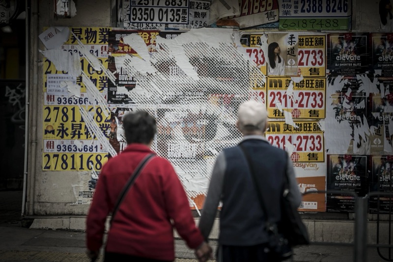 Carved poster wall above a street crowd, Hong Kong