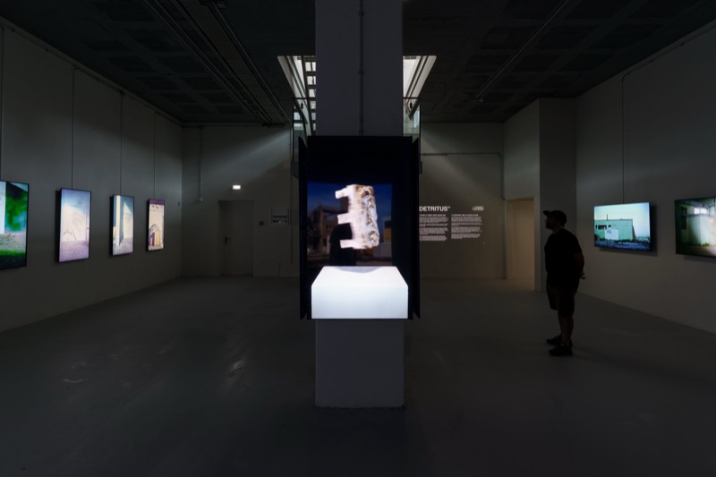 Threshold — DETRITUS dark room with lightboxes and a visitor