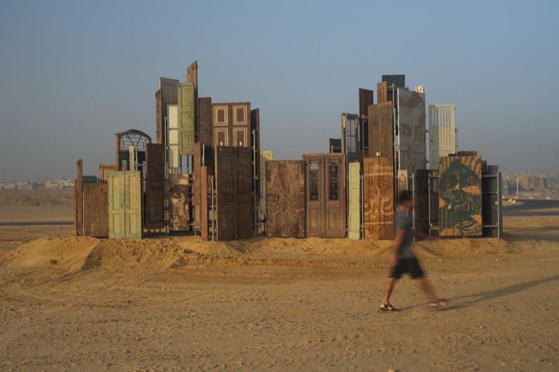 A figure passing the Doors of Cairo monument at golden hour