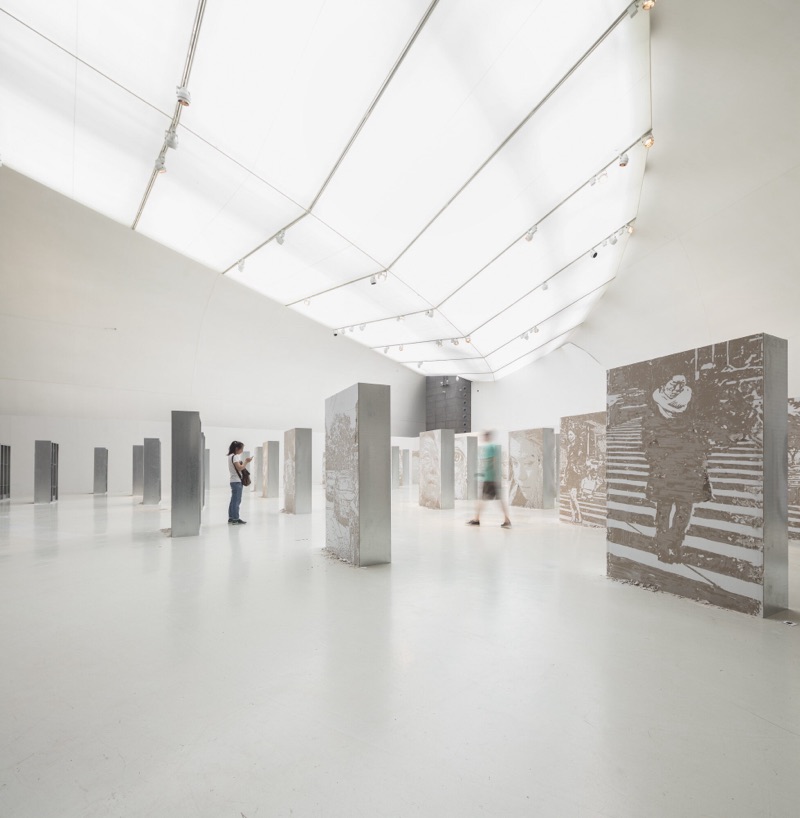 Bas-relief carved-portrait columns and panels in the CAFA gallery interior, with visitors, Beijing