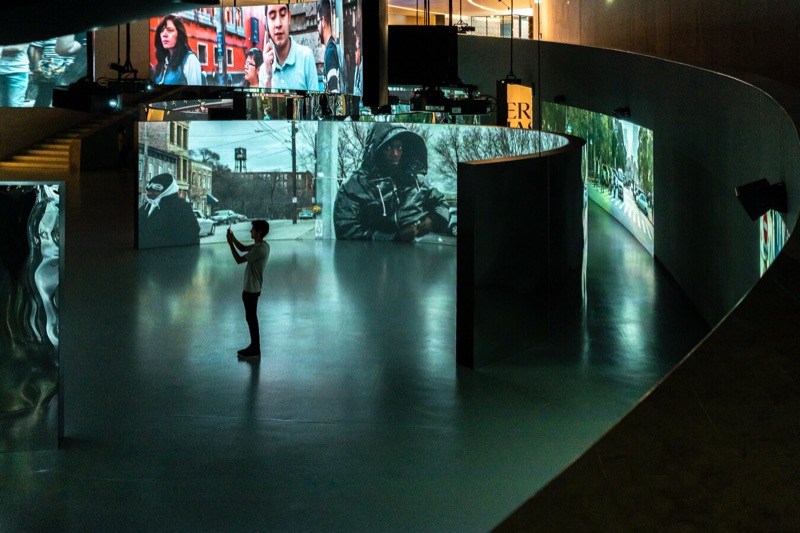 Visitor before the curved video screens inside Prisma