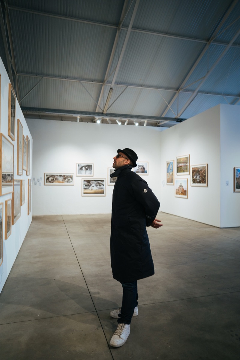 JR alone mid-gallery among the salon-hung walls of Through My Window, Underdogs Gallery, 2025