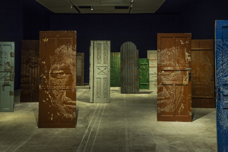 Corridor of carved-portrait doors on dark blue walls, CAIXA Cultural Brasília