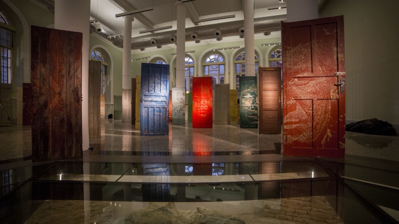 Incisão — wide hall view of the carved Guarani-portrait doors, CAIXA Cultural Recife